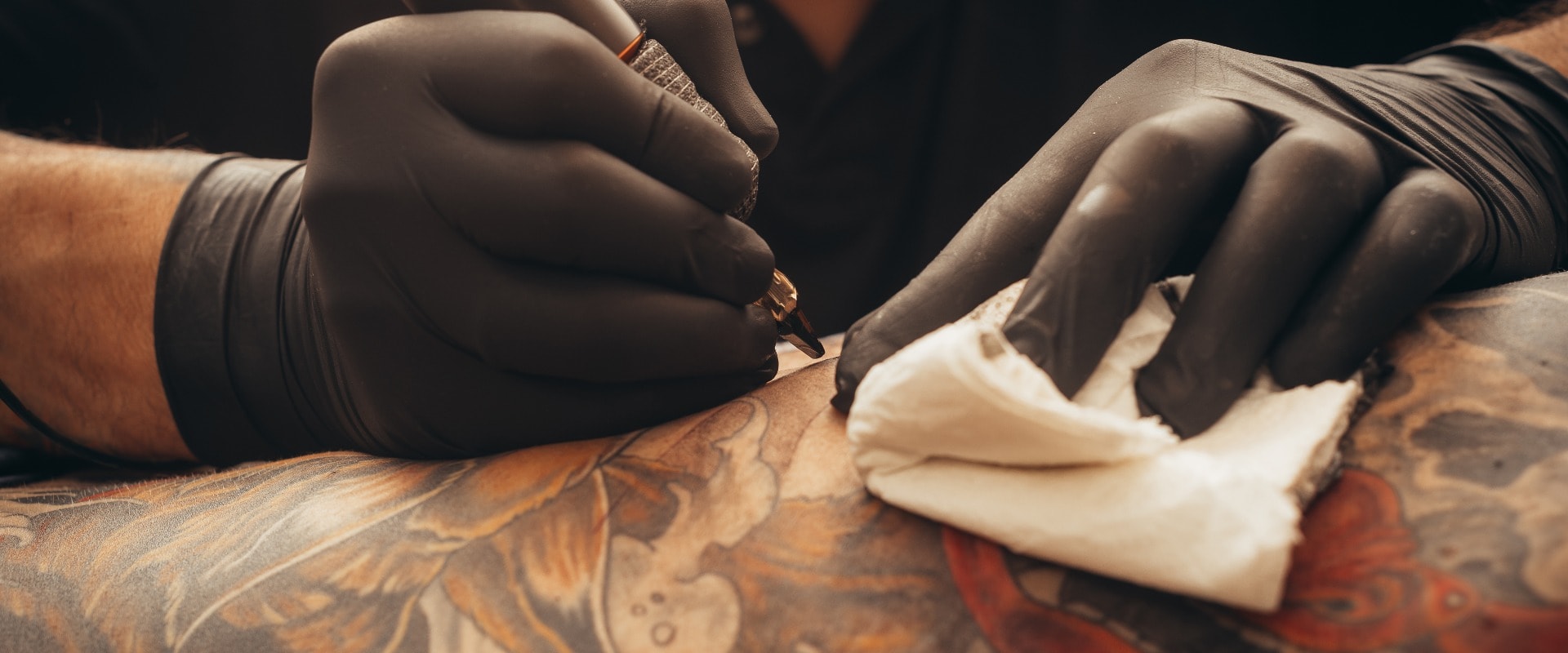 Close up tattoo machine. Tattooing. Man creating picture on his back by a professional tattoo artist.